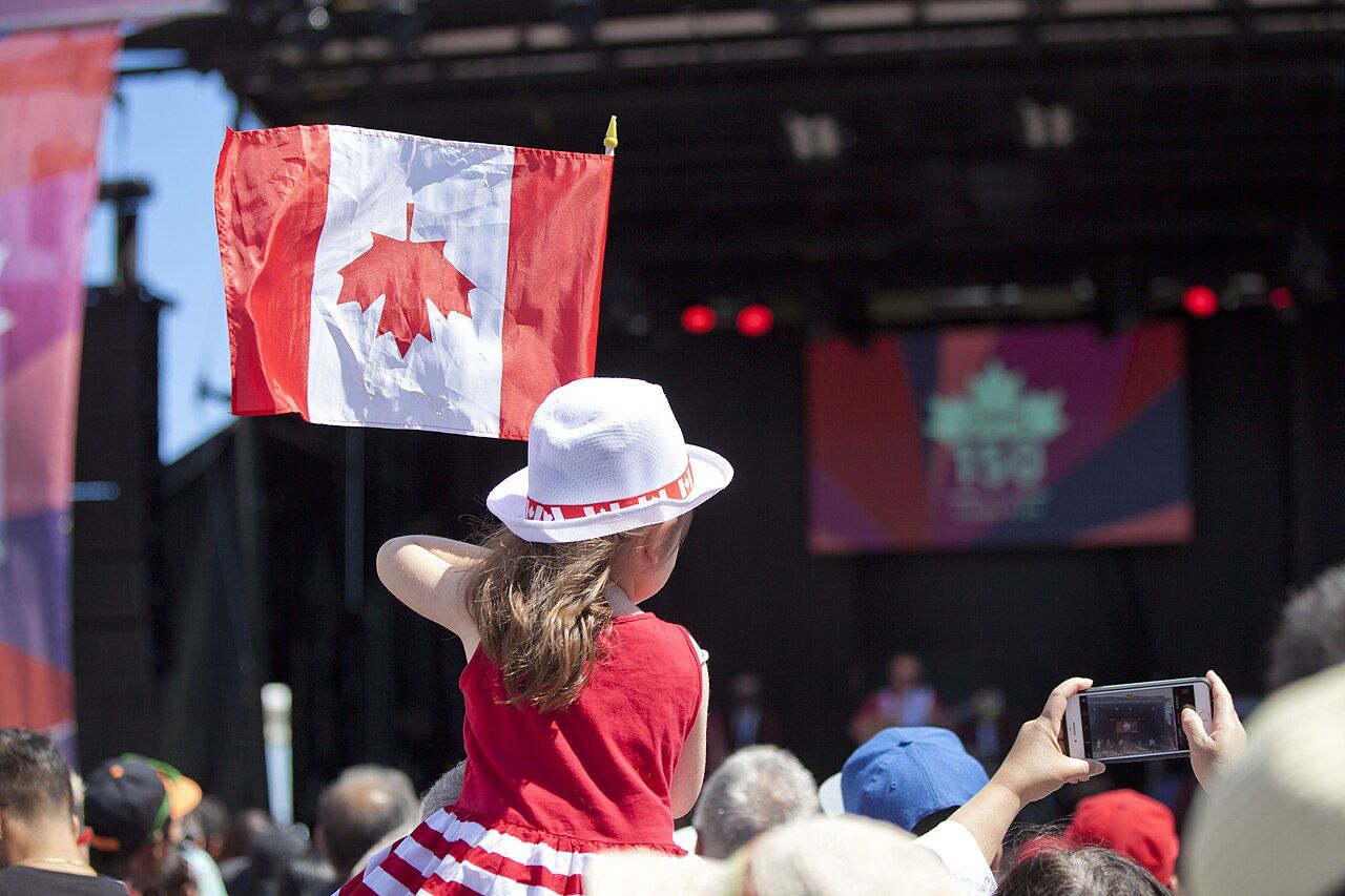A child holding a Canadian flag at a Canada Day celebration
